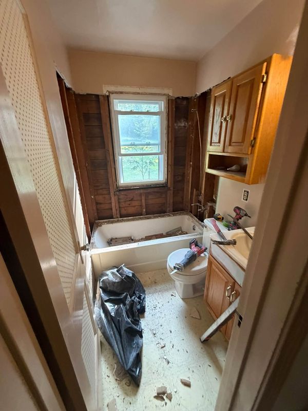 Bathroom stripped to the studs with old tub and demo debris