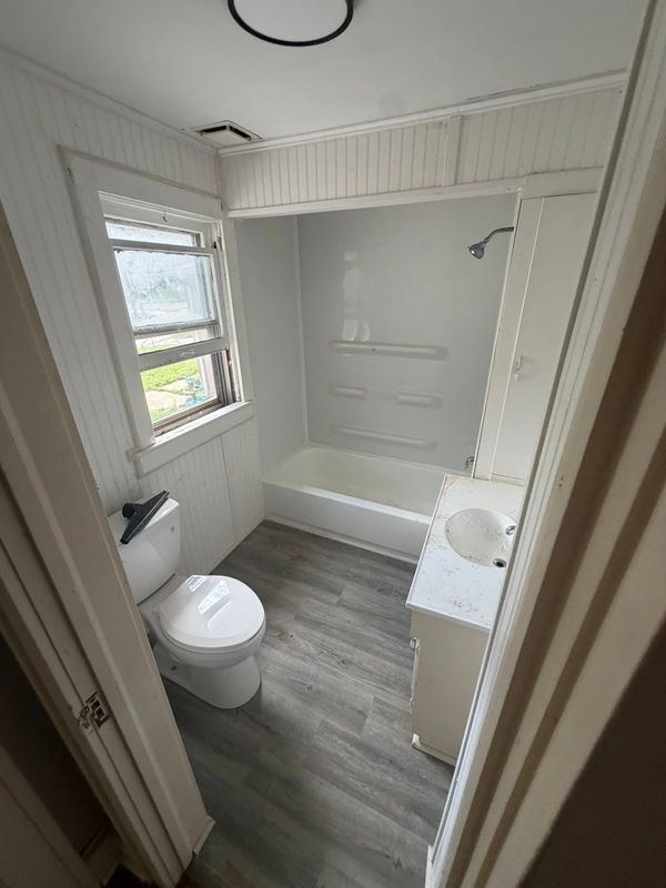 Finished bathroom with tub, shower and gray vinyl plank floor