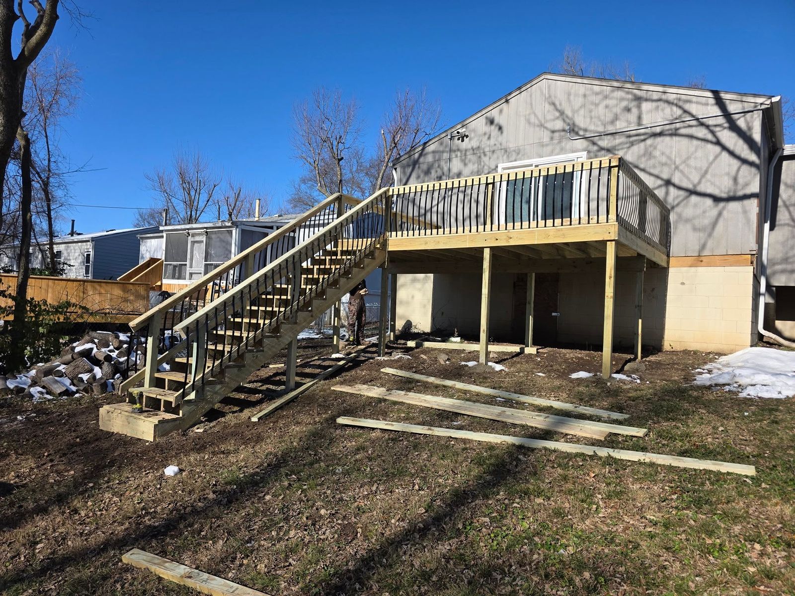 Elevated wood deck on the back of a house with a long stair run down to the yard