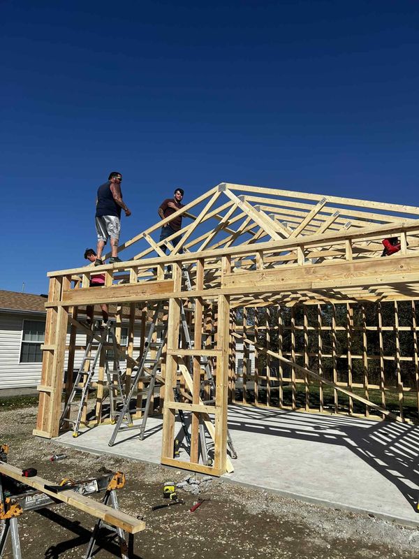 Roof trusses being set on the same garage or shop with the crew working up top