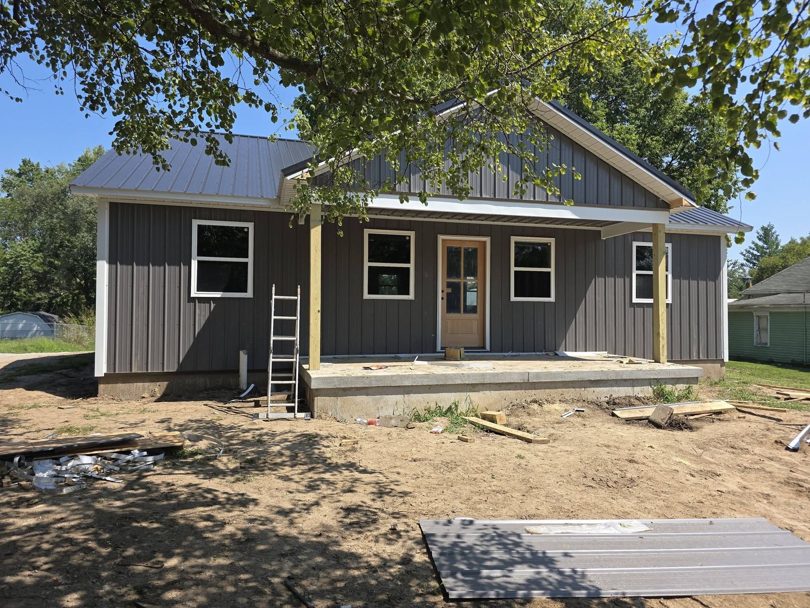 Finished single-story new home with dark vertical siding and a front porch