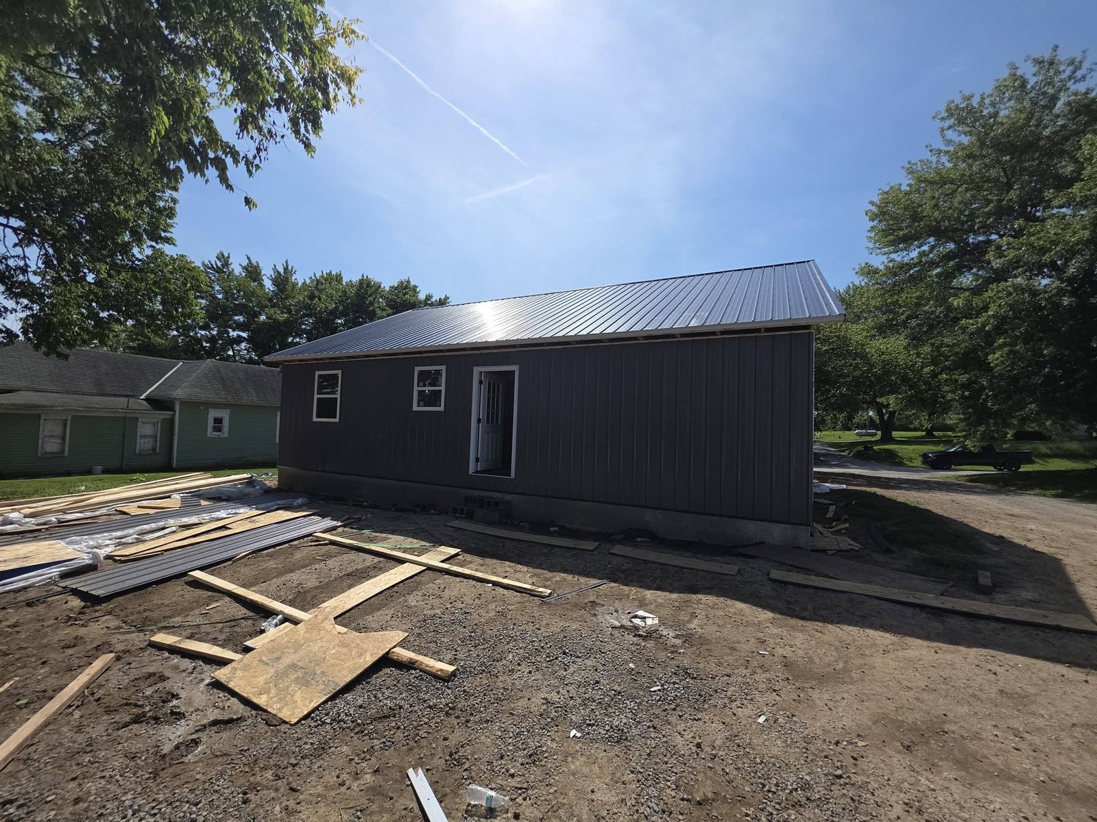 Metal roof on a new home over a graded dirt lot with lumber stacked below