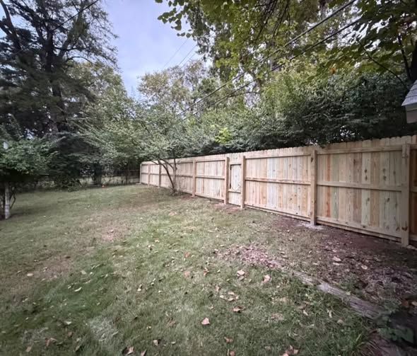 New wood privacy fence across the back of a wooded yard