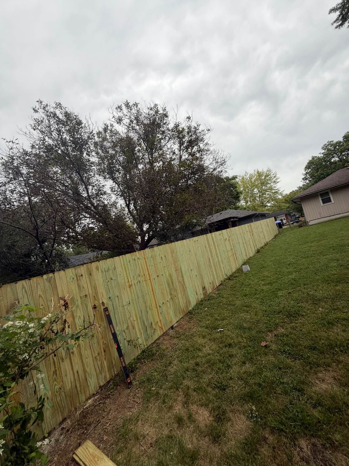 Long new wood privacy fence running down a side yard between two houses