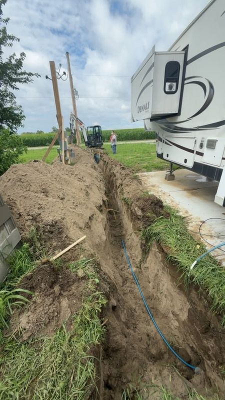 Open trench with a blue water line run out toward an RV