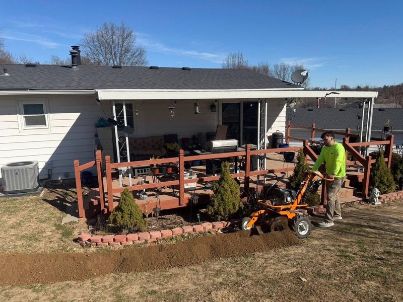 Walk-behind trencher cutting a narrow trench along a landscape bed